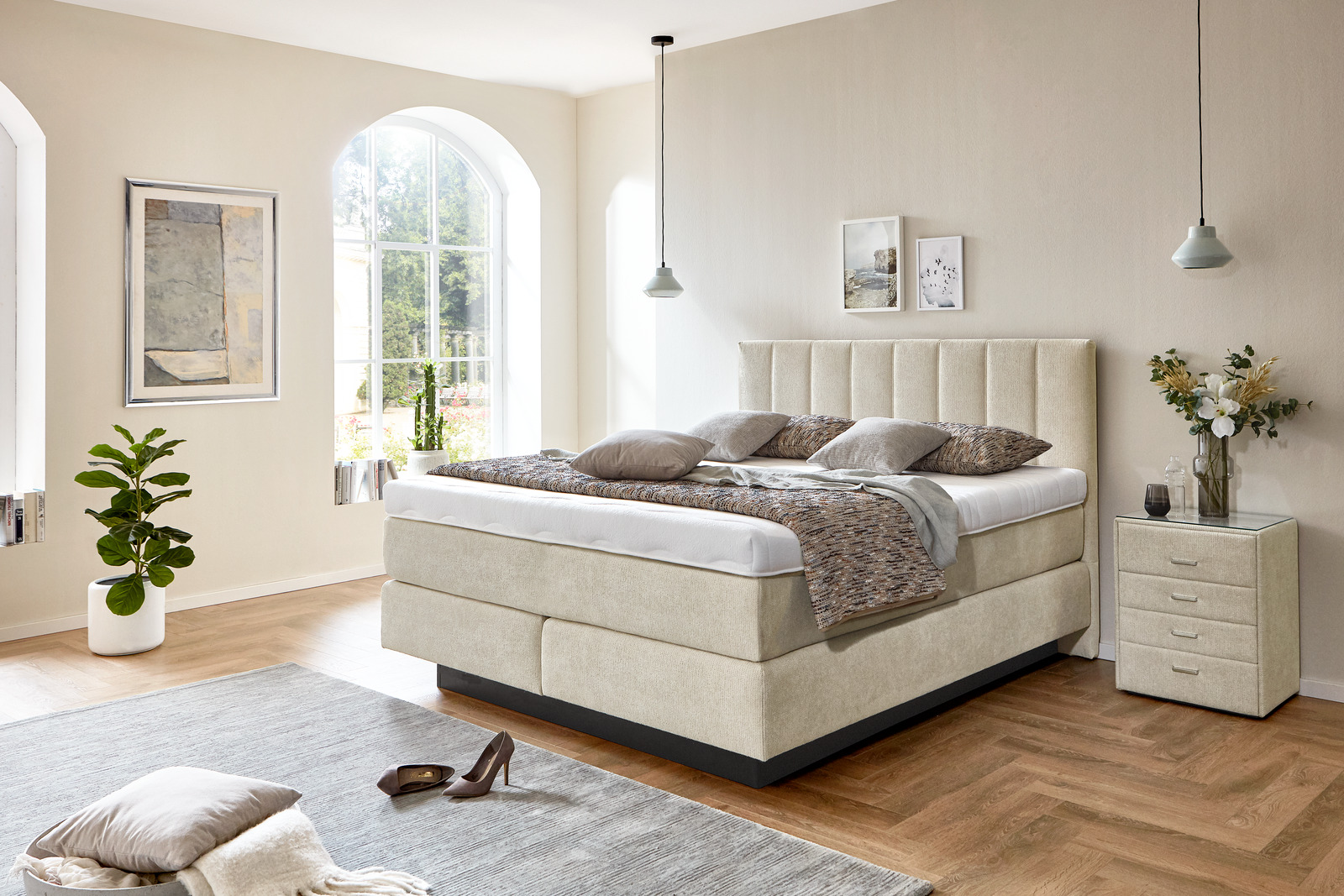 Cremefarbenes Boxspringbett mit passendem Nachttisch in einem hellen Schlafzimmer