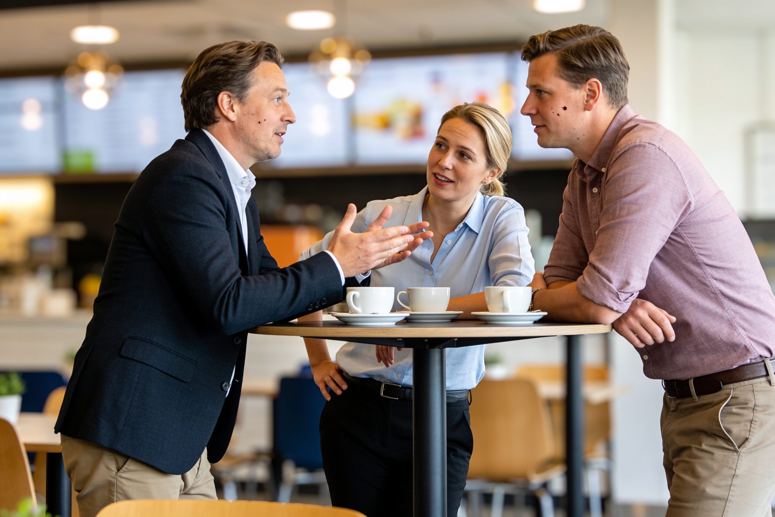 Mitarbeiter im Gespräch an einem Stehtisch in der Betriebskantine