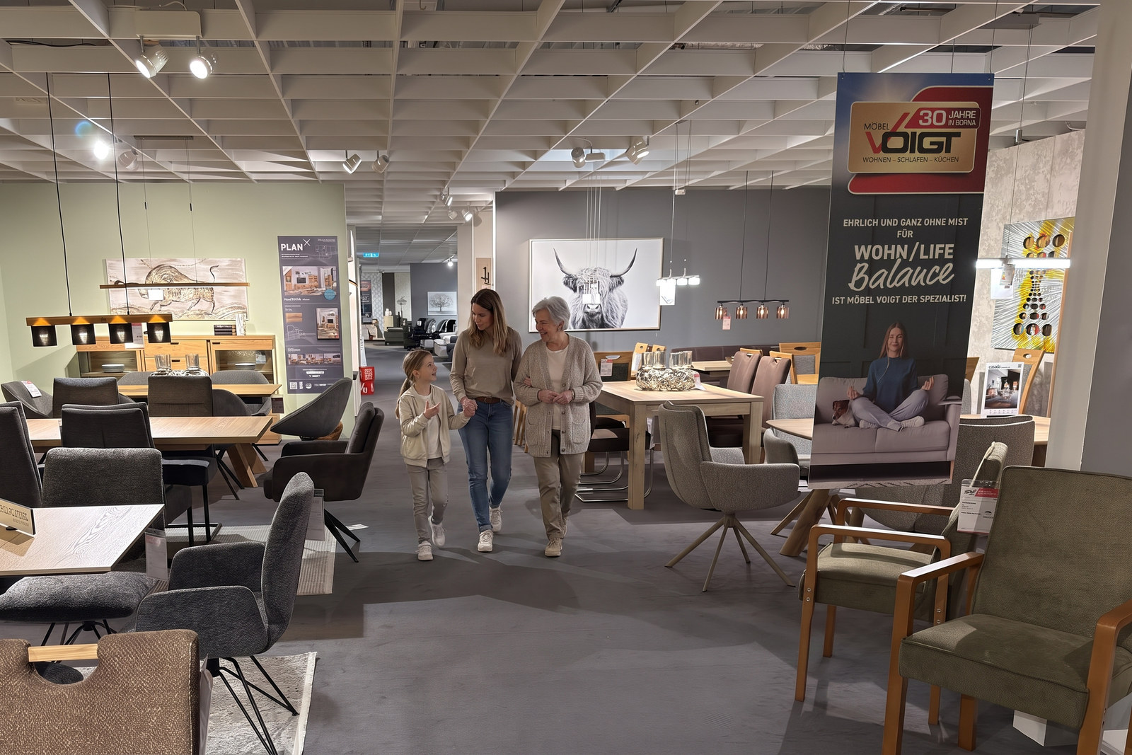 Großmutter, Tochter und Enkelin gehen gemeinsam durch eine Möbelausstellung
