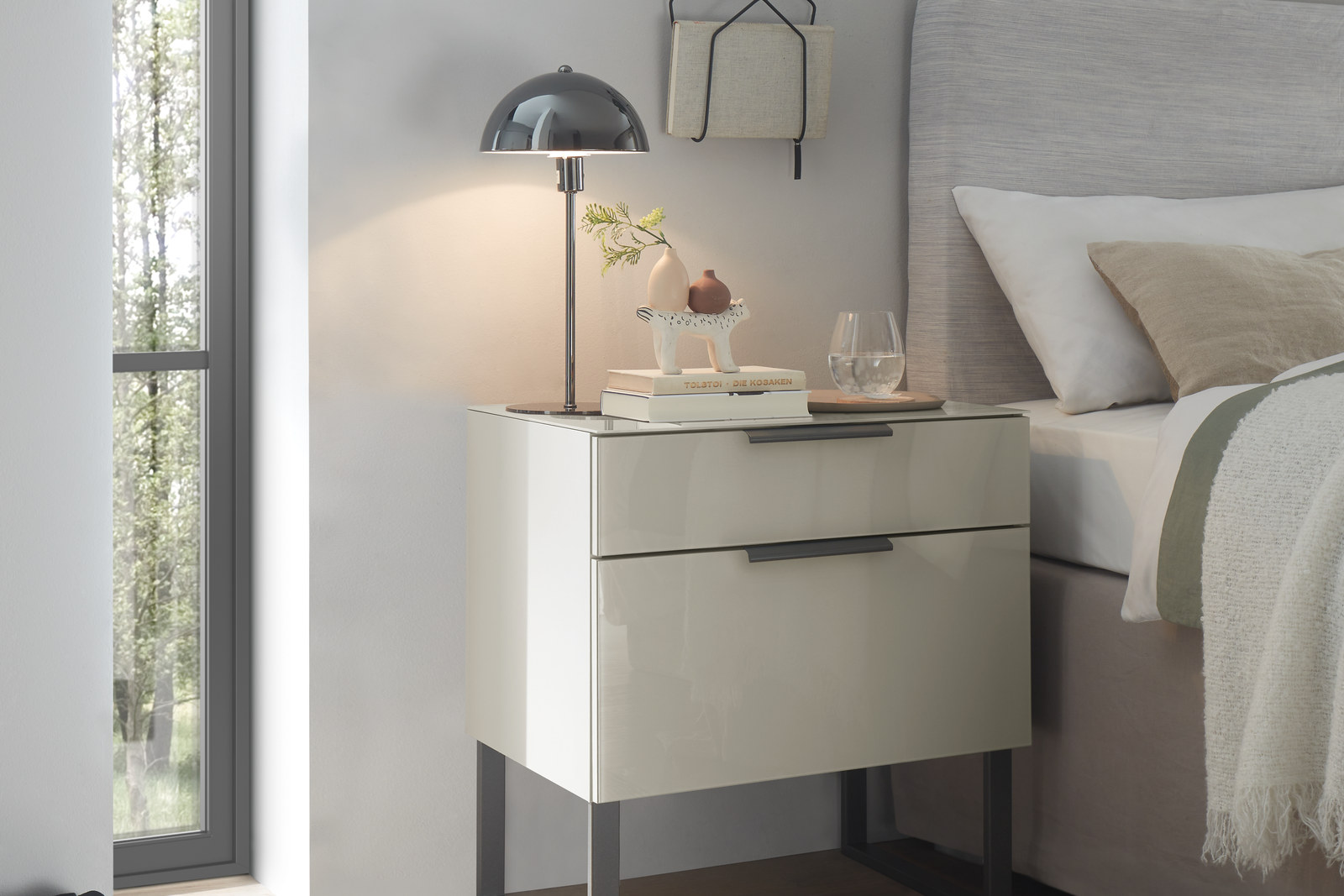 Nachtkonsole mit zwei Schubkästen und Metallfüßen neben einem gepolsterten Bett